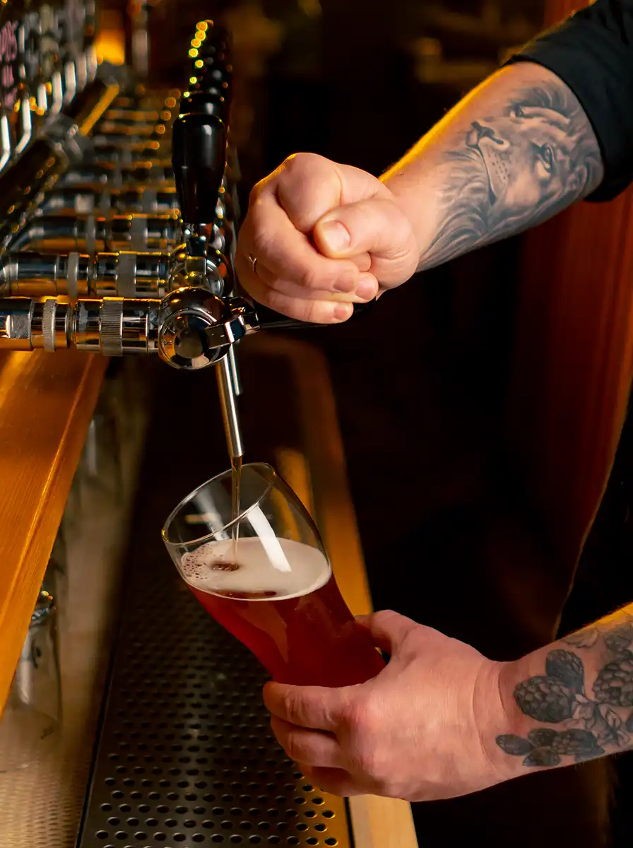 bartender-pouring-craft-beer-into-glass-at-bar https://5x5brewing.com/wp-content/uploads/2026/10/bartender-pouring-craft-beer-into-glass-at-bar.webp